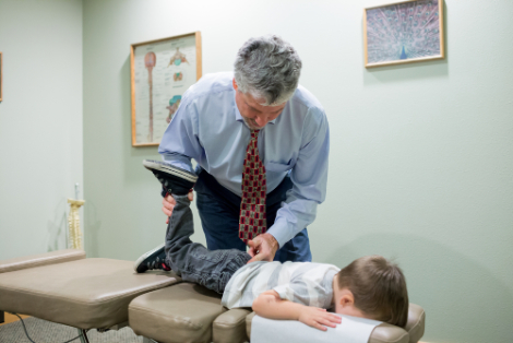 chiropractor assisting a child in chiropractic care